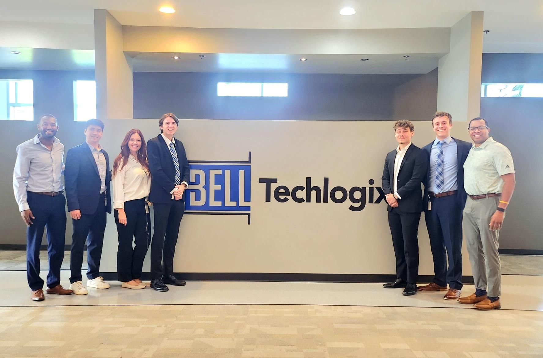 Five Bell Techlogix interns and staff volunteering at the Midwest Food Bank, standing beside a bronze Indiana-shaped donor plaque